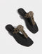 Black sandals with gold embellishments on a white background