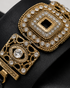 Close up of Aurista black flat sandals highlighting intricate antique gold embellishments and premium craftsmanship.