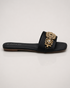 Side view of black embellished flat sandals with elegant antique gold accents and slip on design.