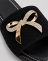Close up of Aveen black flat sandals featuring embellished bow detail