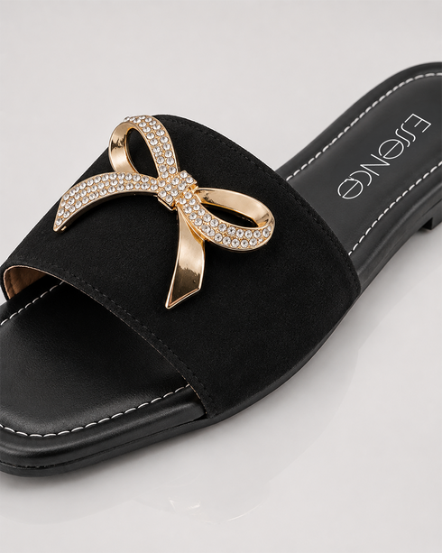 Close up of Aveen black flat sandals featuring embellished bow detail