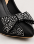 Close up of black pointed toe heels with sparkling rhinestone bow embellishment