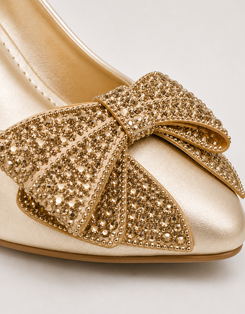 Close up of golden crystal embellished bow on pointed toe women's formal heels