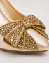 Close up of golden crystal embellished bow on pointed toe women's formal heels