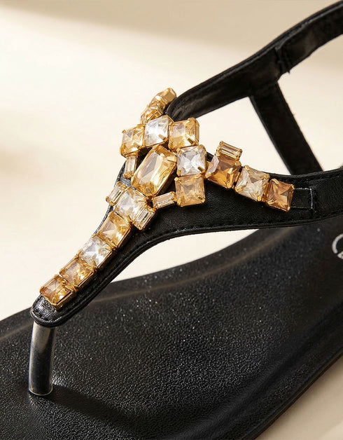 Close-up of black T-strap sandals featuring gold crystal rhinestone embellishment, premium quality women sandals, fancy flat sandals for parties and casual wear Pakistan