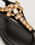 Close-up of black T-strap sandals featuring gold crystal rhinestone embellishment, premium quality women sandals, fancy flat sandals for parties and casual wear Pakistan