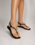 Women wearing black crystal embellished T-strap sandals with gold rhinestone detailing, open toe flat sandals for summer, comfortable ladies footwear Pakistan, stylish casual and formal sandals