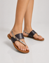 Model wearing brown flat sandals with textured strap detail