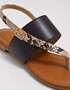 Close up of brown flat sandals with snake textured strap
