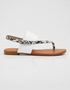 Side profile of white flat sandals with slip on design