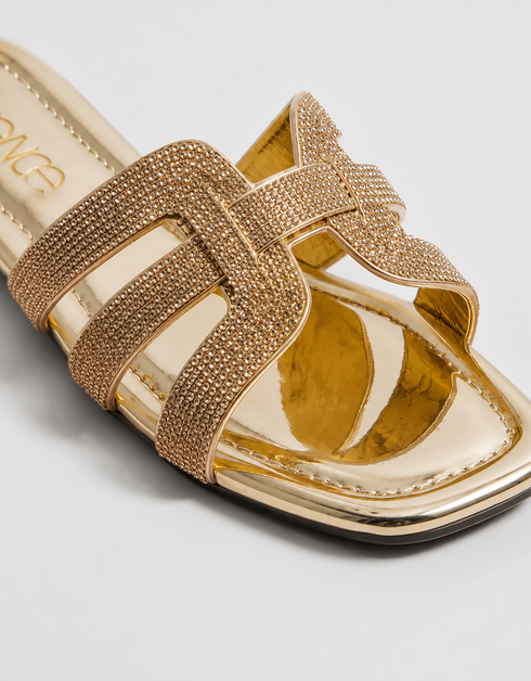 Close up of gold shimmer flat sandals highlighting the textured multi strap craftsmanship.
