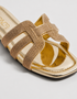 Close up of gold shimmer flat sandals highlighting the textured multi strap craftsmanship.