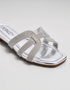 Side view of silver shimmer flat sandals featuring lightweight slip on construction.