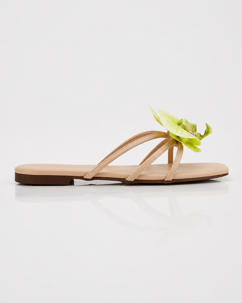 Side view of beige floral flat sandals featuring an orchid flower accent and lightweight slip on design.