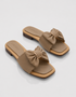 Pair of beige bow flat sandals with oversized bow detail and soft cushioned sole.