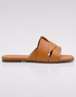 Side view of tan flat sandals with clean overlapping strap design.