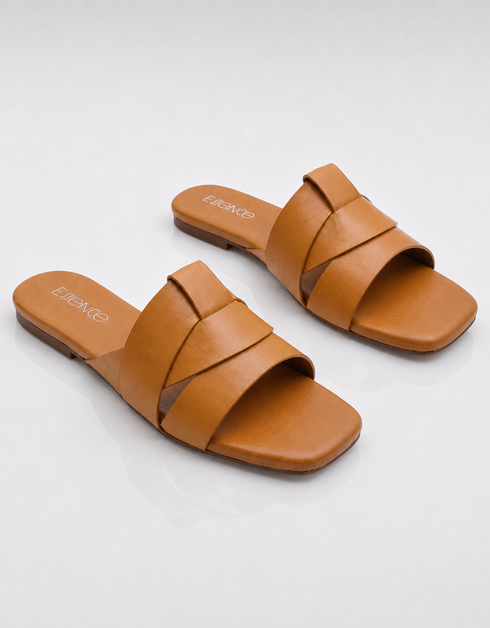 Pair of tan flat sandals with minimalist overlapping straps and cushioned footbed.