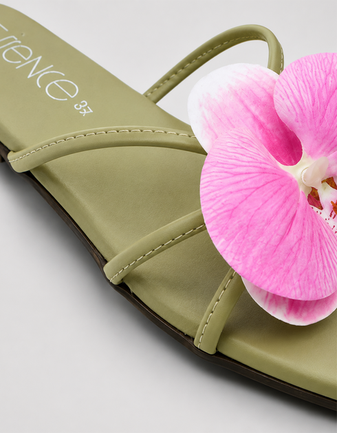 Close-up of pink orchid flower embellishment on olive green flat sandal padded sole
