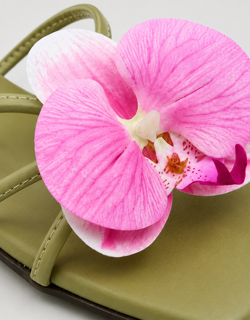Close-up of pink orchid flower embellishment on olive green flat sandal padded sole