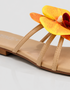 Close-up of yellow orchid flower embellishment on flat sandal with padded sole