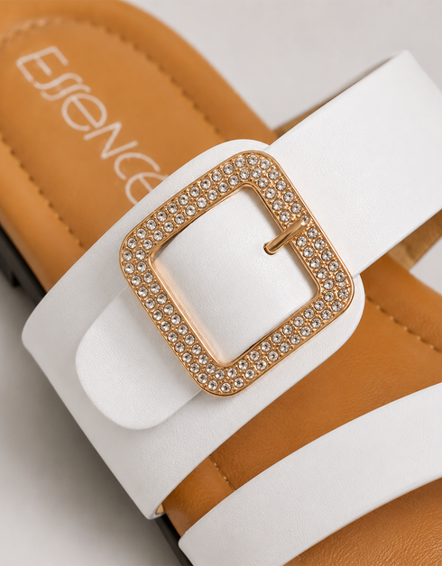 Close up of white dual strap sandals highlighting the statement buckle and premium finish.