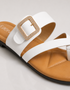 Close up of white dual strap sandals highlighting the statement buckle and premium finish.