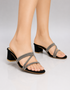 Woman wearing black embellished low block heel slippers with elegant shimmer straps for