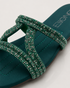 Close up of teal embellished flat sandals highlighting the shimmering strap detailing and premium craftsmanship.