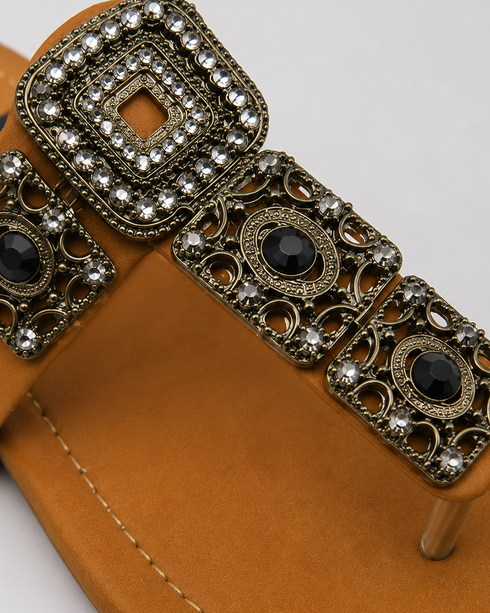 Close-up of antique gold buckle and embellishment on Mustard Kolhapuri flat sandal