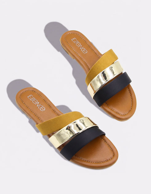 Pair of mustard flat sandals with bold dual straps and metallic detailing.