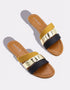Pair of mustard flat sandals with bold dual straps and metallic detailing.
