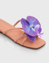 Close-up of purple orchid flower embellishment on flat sandal with padded sole