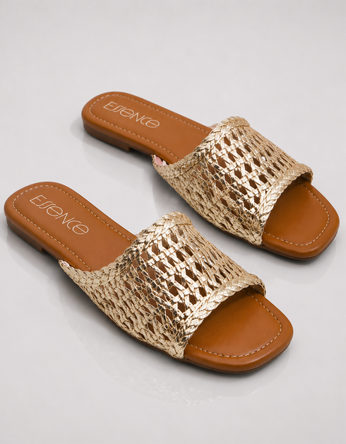 Gold woven slide sandals with brown soles on a light gray background