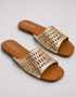 Gold woven slide sandals with brown soles on a light gray background