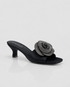 Black sandal with a decorative flower on a white background