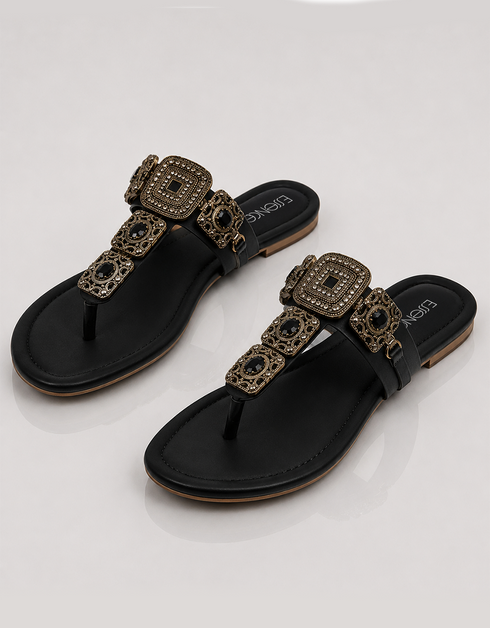 Black sandals with gold embellishments on a white background