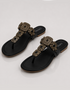 Black sandals with gold embellishments on a white background