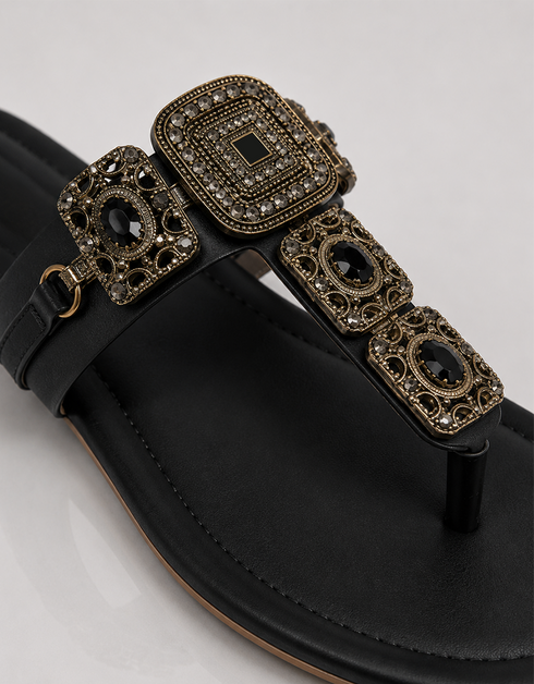 Black sandal with decorative buckle on a light gray background