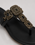 Black sandal with decorative buckle on a light gray background